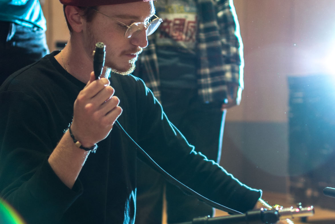 student with xkr cable in hand setting up reording session in the citrus college recording studio