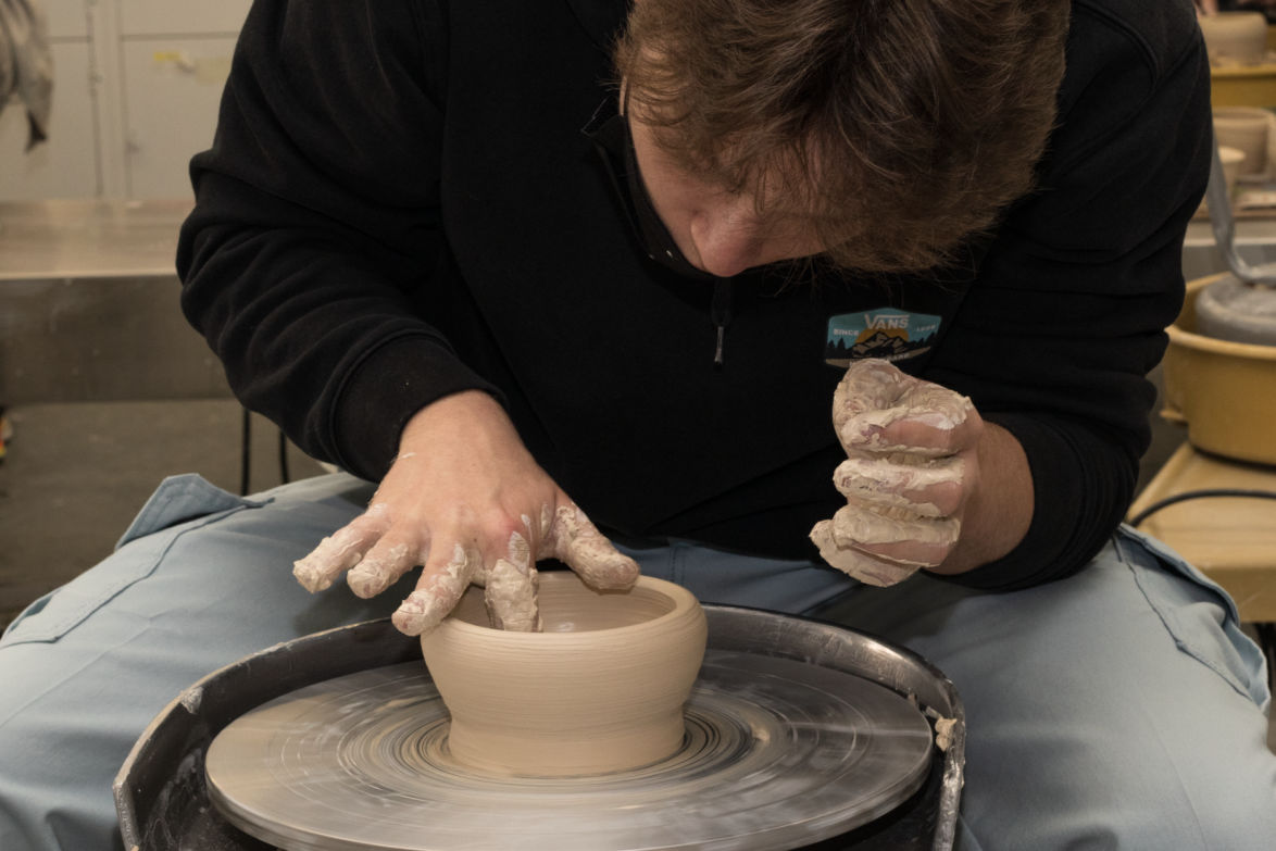 student working with clay on a clay wheel